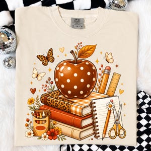 PNG de estampa de leopardo, maçã e pilha de livros com estampa floral xadrez, ideal para sublimação e para a volta às aulas. Download digital para camisetas de professores.