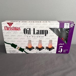 May include: A rectangular product box for Hofort's Christmas C7 Flicker Oil Lamp set. The white box features purple accents, text reading "Christmas C7 Flicker Oil Lamp," and illustrations of three lamps with green holly bases and glowing orange flames.
