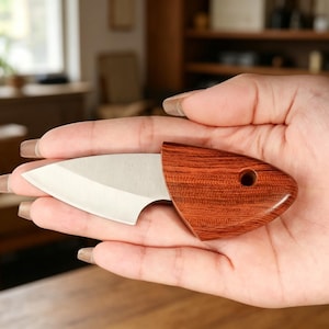 May include: A small, stainless steel knife with a wooden handle. The handle is a reddish-brown color with a visible wood grain pattern. The knife is held in a hand.