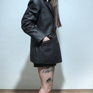 tattooed model wearing black leather blazer with high waisted leather shorts and ankle boots