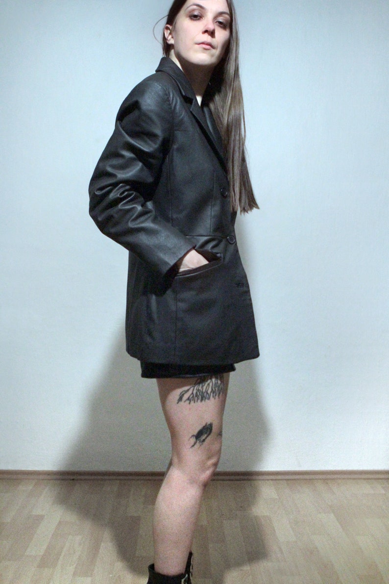 tattooed model wearing black leather blazer with high waisted leather shorts and ankle boots