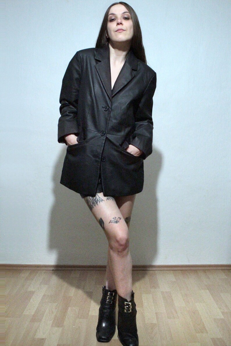 tattooed model wearing black leather blazer with high waisted leather shorts and ankle boots