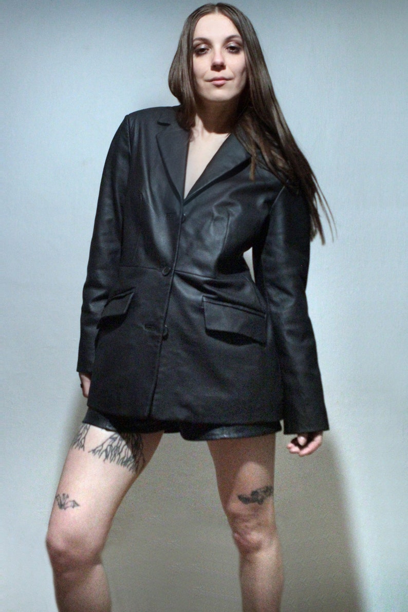 tattooed model wearing black leather blazer with high rise leather shorts