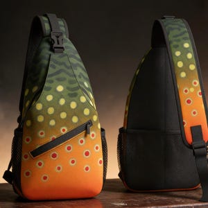 May include: A sling bag with a brown trout pattern. The bag features a green and brown camouflage pattern at the top, transitioning to a yellow and orange spotted design. It has a black strap, zipper, and mesh side pocket.