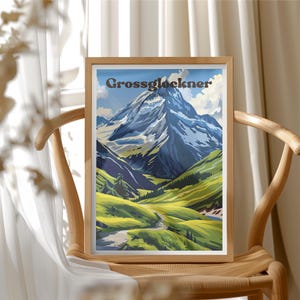 以下が含まれることがあります： 「Grossglockner」の文字が上部に書かれた、山の風景の額入りプリント。雪をかぶった山、緑の谷、曲がりくねった道が描かれています。フレームは明るい色の木材で作られています。