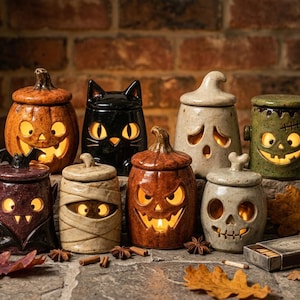 Puede incluir: Una colección de ocho tarros de cerámica con temática de Halloween y tapas, que incluyen una calabaza, un gato negro, un fantasma, el monstruo de Frankenstein, un vampiro, una momia, una calabaza iluminada y una calavera, todos iluminados.