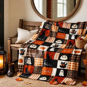 Peut inclure: Un plaid doux présentant un motif patchwork composé de chats noirs, de fantômes blancs, de citrouilles orange et de motifs à carreaux noirs, orange et blancs. Le tissu comporte le mot Spooky écrit en lettres cursives blanches répétées.