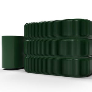 Puede incluir: Un juego de almacenamiento verde oscuro de estilo moderno. El juego incluye un recipiente cilíndrico y una pila de tres bloques rectangulares. Cada bloque y el recipiente tienen una textura acanalada. Los objetos están sobre un fondo blanco.