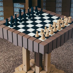 Könnte beinhalten: Ein Schachspiel mit einem braun-schwarzen Schachbrett und einem braunen Rand. Die Schachfiguren sind schwarz und cremefarben. Das Schachspiel steht auf einem Tisch mit braunem und beigem Design.