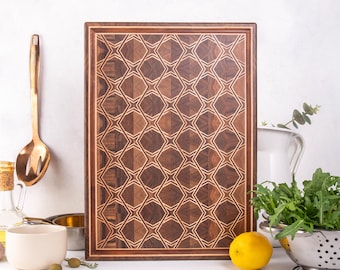May include: A rectangular wooden cutting board with a geometric pattern. The board features a dark brown border and a detailed design of interlocking shapes in varying shades of brown and tan. Kitchen items like a spoon, bowl, and lemon are in the foreground.