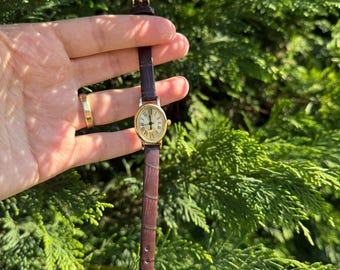 Women's wristwatch with dark brown and black leather strap.