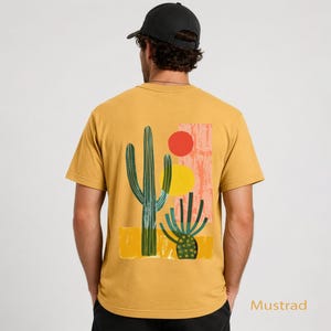 Puede incluir: Una camiseta de manga corta color amarillo mostaza con un estampado gr&aacute;fico en la espalda. El dise&ntilde;o muestra dos cactus verdes, un c&iacute;rculo rojo, un c&iacute;rculo amarillo y una forma rectangular rosa texturizada sobre un fondo amarillo.
