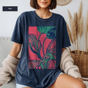 May include: Navy blue t-shirt featuring a vibrant floral design. The graphic showcases green and blue botanical illustrations against a red backdrop. The shirt has a relaxed fit and short sleeves, perfect for casual wear.