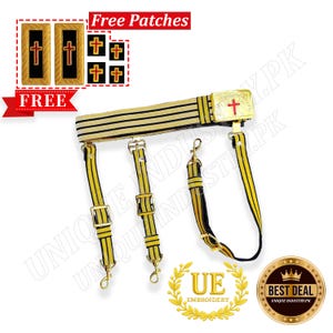 Puede incluir: Un cinturón militar dorado y negro con tres tirantes. El cinturón tiene una hebilla dorada con una cruz roja. La imagen también muestra parches con cruces y el texto "Free Patches".
