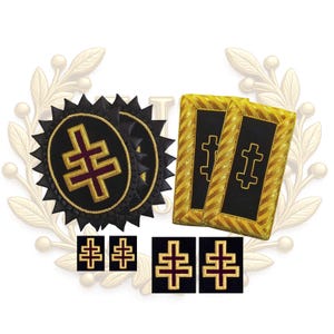 Könnte beinhalten: Eine Sammlung bestickter Aufnäher und rechteckiger Schulterstücke mit schwarzem Hintergrund und einem bordeaux-goldenen Doppelkreuz-Emblem. Das Set enthält zwei runde Aufnäher mit gezacktem Rand, zwei rechteckige Schulterstücke und vier kleine quadratische Aufnäher.