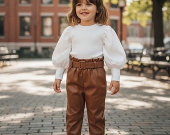 Conjunto de dos piezas para niña: blusa acanalada y pantalón de piel sintética con cinturón.