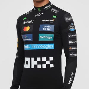 Könnte beinhalten: Schwarzes Langarmshirt mit Stehkragen, mit Sponsorenlogos und dem McLaren-Logo. Das Shirt hat ein Schachbrettmuster auf der Vorderseite und den Text "OKX". Die Ärmel tragen die Texte "HIGEIUH" und "sparco".