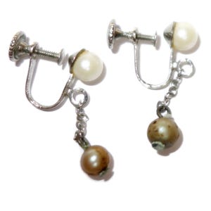 May include: A pair of vintage clip-on earrings. Each earring features a silver-toned screw-back mechanism, a small cream-colored pearl, and a dangling chain with a brown pearl-like bead. The earrings are set against a white background.
