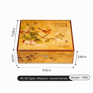 Puede incluir: Un humidor de madera con un diseño de pájaro y flores en la tapa. El humidor mide 24 cm de largo, 18.5 cm de alto y 6.6 cm de profundidad. Puede contener 20-30 cigarros y pesa 1.9 kg. El texto "Luxe Humidor" y "Harvest Season" son visibles.