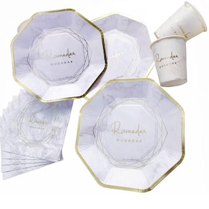 May include: A collection of Ramadan-themed party supplies. The set includes octagonal plates, cups, and napkins with a marble-like pattern and gold trim. The word "Ramadan Mubarak" is printed in gold on each item.