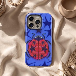 May include: A blue phone case featuring a red ladybug design with black star accents. The ladybug has a red body with black star patterns. The background is blue with white starburst shapes.