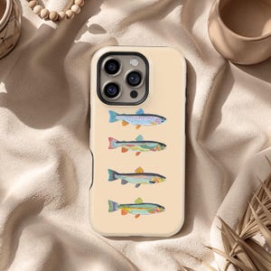 May include: A beige phone case featuring four colorful illustrations of fish. Each fish has a unique pattern of blues, reds, yellows, and greens. The case has a black camera lens border and a beige background.