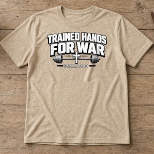 Puede incluir: Una camiseta de manga corta en color beige jaspeado con el texto en blanco y negro TRAINED HANDS FOR WAR, un gr&aacute;fico de una barra de pesas con una cruz en el centro y el texto PSALM 144:1 impreso en el pecho.
