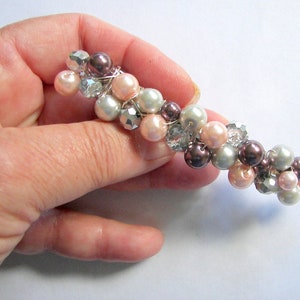 May include: A beaded hair clip with pink, white, and brown pearls and clear rhinestones.