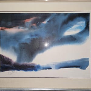 May include: Abstract watercolor painting in a silver frame. The artwork features a dramatic sky with shades of blue, black, and hints of pink. The bottom of the painting has a dark blue and purple landscape.