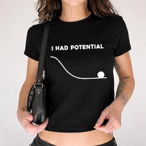 Può includere: Top corto nero con la scritta bianca "I HAD POTENTIAL". Un grafico bianco raffigura una palla che rotola giù per un pendio. Questo top casual è adatto all'uso quotidiano.