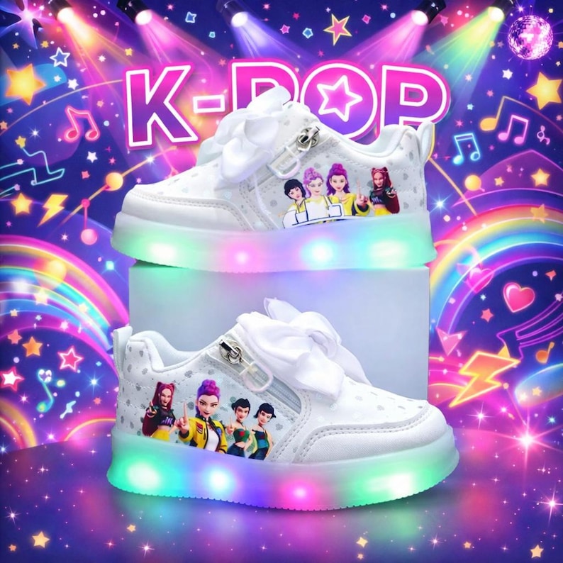 Puede incluir: Zapatillas blancas con tem&aacute;tica K-POP, con suela luminosa LED arco&iacute;ris. Los zapatos tienen una cremallera lateral, un lazo blanco y un gr&aacute;fico de personajes animados. El fondo tiene el texto "K-POP" y notas musicales.