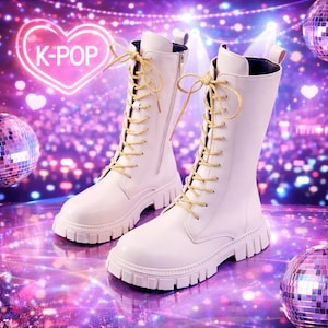 May include: A pair of white, mid-calf boots with thick soles and gold-colored laces. The boots have a zipper on the side and are set against a blurred background with a neon heart-shaped sign that says "K-POP".