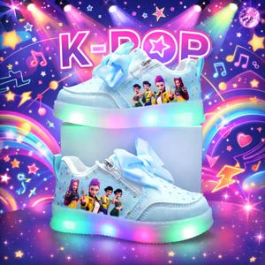 Puede incluir: Zapatillas deportivas K-Pop azul claro con luces LED de colores alrededor de las suelas. Los zapatos tienen un lazo, cremallera y un gr&aacute;fico de dibujos animados de personajes. El fondo tiene el texto "K-POP" y notas musicales.