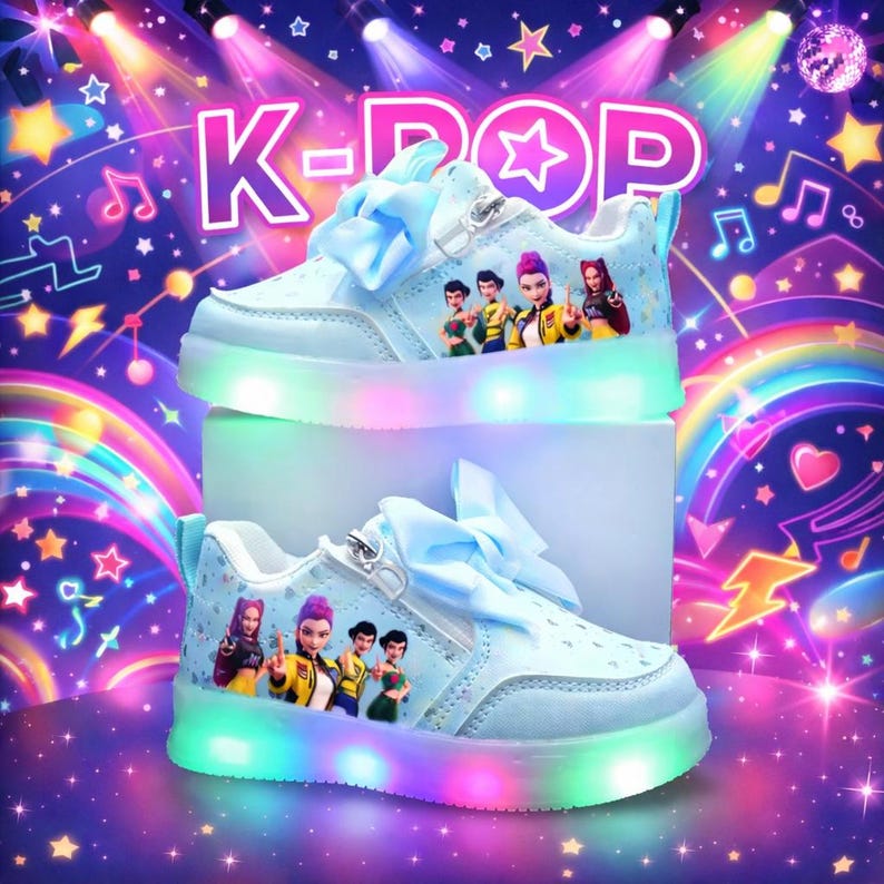 Puede incluir: Zapatillas deportivas K-Pop azul claro con luces LED de colores alrededor de las suelas. Los zapatos tienen un lazo, cremallera y un gr&aacute;fico de dibujos animados de personajes. El fondo tiene el texto "K-POP" y notas musicales.
