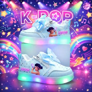 Puede incluir: Zapatillas de deporte azul claro con tem&aacute;tica K-Pop con luces LED. Los zapatos presentan un gr&aacute;fico de dibujos animados de una ni&ntilde;a, un lazo azul claro y las palabras "Demon Hunters K-Pop". Las suelas de los zapatos tienen una luz LED arco&iacute;ris.