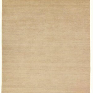 May include: A rectangular, beige rug with a textured surface. The rug has a simple, neutral design, suitable for various interior styles. The edges of the rug have a slightly frayed appearance.