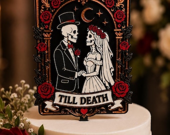 May include: A black and gold cake topper featuring a skeleton couple in wedding attire, surrounded by red roses and a crescent moon. The rectangular frame includes the text TILL DEATH on a banner at the bottom, set atop a white tiered cake.