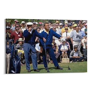 Puede incluir: Fotografía vintage de dos hombres con cárdigans y pantalones azules en un campo de golf, rodeados por una multitud de espectadores. Uno de los hombres sostiene un palo de golf, mientras que el otro parece estar fumando. La escena tiene lugar en un césped verde.