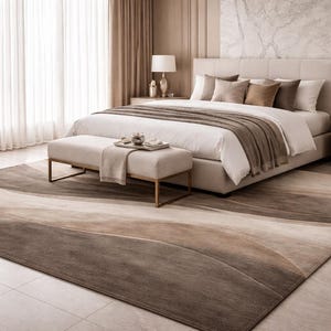 May include: A bedroom scene featuring a large bed with a neutral color palette. The room includes a patterned rug in shades of brown and beige, a bench, dressers, and a round mirror. Soft curtains and a lamp add to the ambiance.