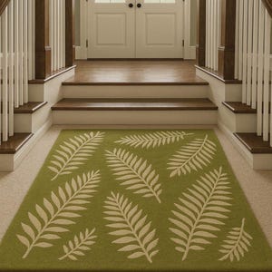May include: A green rectangular rug with a repeating pattern of large, off-white fern leaves. The rug is placed on a beige carpeted floor in front of a set of stairs leading to a white door with glass panels.