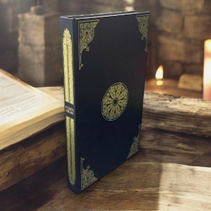 May include: A dark blue book with gold decorative accents and a central circular design. The spine features the text "Codex Gigas" in gold. The book is standing upright on a wooden surface.