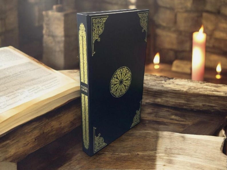 May include: A dark blue book with gold decorative accents and a central circular design. The spine features the text "Codex Gigas" in gold. The book is standing upright on a wooden surface.