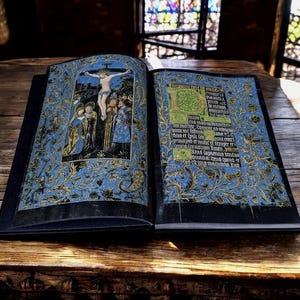 May include: An open book with black covers featuring illuminated manuscript pages. The left page displays a crucifixion scene, while the right page contains Latin text with a large green initial letter. Both pages have blue borders with gold floral patterns.