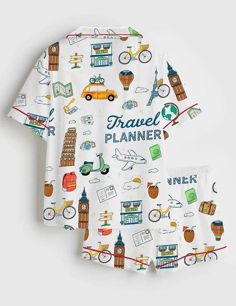 May include: White pajama set with a travel theme. The short-sleeved top and shorts feature a repeating pattern of travel icons, including bicycles, landmarks, and the text "Travel Planner". Red trim accents the edges.