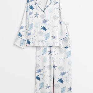 Peut inclure: Ensemble de pyjama blanc avec un motif bleu sur le th&egrave;me de la mer. L'ensemble comprend un haut boutonn&eacute; et un pantalon assorti. Le motif pr&eacute;sente des tortues de mer bleues, des coquillages, des &eacute;toiles de mer et des motifs floraux.