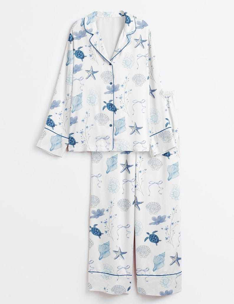 Peut inclure: Ensemble de pyjama blanc avec un motif bleu sur le th&egrave;me de la mer. L'ensemble comprend un haut boutonn&eacute; et un pantalon assorti. Le motif pr&eacute;sente des tortues de mer bleues, des coquillages, des &eacute;toiles de mer et des motifs floraux.