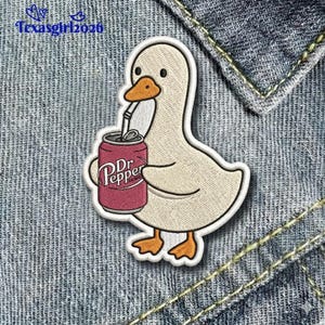 May include: Embroidered patch featuring a cartoon goose holding a Dr. Pepper can with a straw. The goose is off-white with an orange beak and feet. The Dr. Pepper can is red with white lettering. The patch is on a denim background.