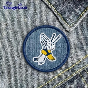 May include: A round, blue denim patch with a golf-themed design. The patch features a white wing, golf clubs, and a yellow and black golf shoe. The text "Texasgirl2020" is in the upper left corner.