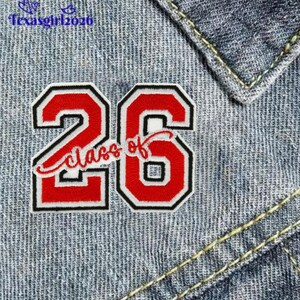 May include: A red and white embroidered patch with the number "26" and the words "Class of" in a script font. The patch has a black border and is set against a denim background.