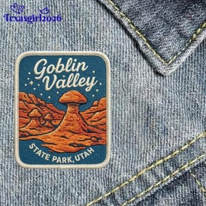May include: A rectangular embroidered patch featuring a landscape of orange and brown rock formations against a dark blue sky with white stars. The text reads Goblin Valley State Park, Utah in white lettering. The patch is attached to blue denim.